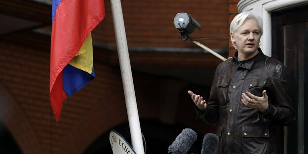 Julian Assange steht redend auf einem Balkon, links neben ihm die ecuadorianische Flagge Julian Assange steht redend auf einem Balkon, links neben ihm die ecuadorianische Flagge
