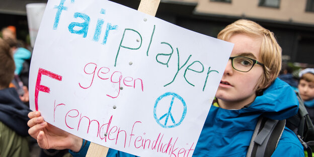 Ein Schüler hält bei einer Demonstration ein Schild mit der Aufschrift "fairplayer gegen Fremdenfeindlichkeit" hoch. Ein Schüler hält bei einer Demonstration ein Schild mit der Aufschrift "fairplayer gegen Fremdenfeindlichkeit" hoch.