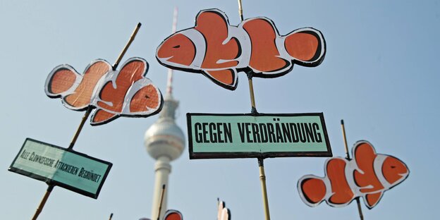 Bei einer Dmeonstration gegen drastisch steigende Mieten in Berlin werden Schilder mit Fischen und der Aufschrift „Gegen Verdrängung“ in die Höhe gehalten Bei einer Dmeonstration gegen drastisch steigende Mieten in Berlin werden Schilder mit Fischen und der Aufschrift „Gegen Verdrängung“ in die Höhe gehalten