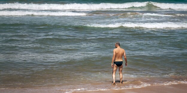 Mann mit schwarzer Badehose am Strand Mann mit schwarzer Badehose am Strand