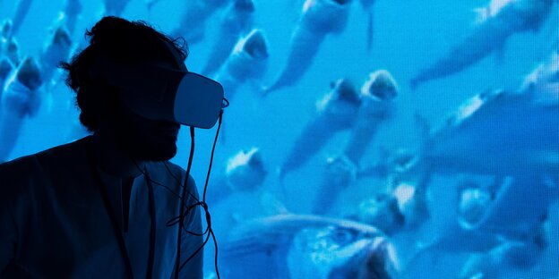 Ein Mann vor einem Aquarium mit Fischen Ein Mann vor einem Aquarium mit Fischen