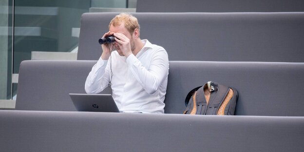 Ein Journalist beobachtet die Sitzung des Bundestages mit dem Fernglas von der Pressetribüne aus. Ein Journalist beobachtet die Sitzung des Bundestages mit dem Fernglas von der Pressetribüne aus.