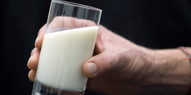 Eine Hand hält ein Glas Milch Eine Hand hält ein Glas Milch