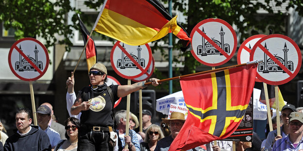 Menschen mit Deutschlandfahnen und Anti-Moschee-Plakaten bei einer Kundgebung Menschen mit Deutschlandfahnen und Anti-Moschee-Plakaten bei einer Kundgebung