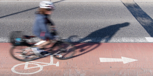 Eine Person fährt auf einem Radstreifen Fahrrad und trägt dabei Helm Eine Person fährt auf einem Radstreifen Fahrrad und trägt dabei Helm