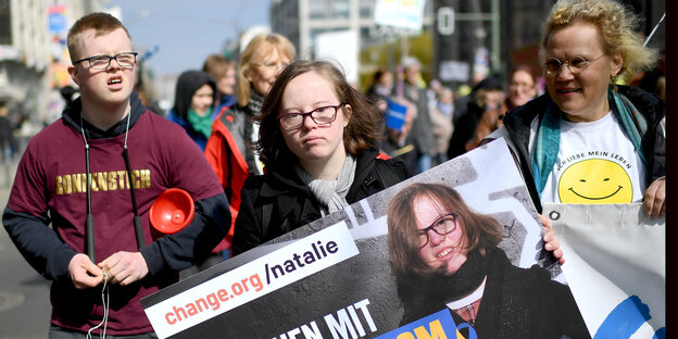Zwei junge Menschen mit Downsyndrom halten ein Plakat auf einer Demo Zwei junge Menschen mit Downsyndrom halten ein Plakat auf einer Demo