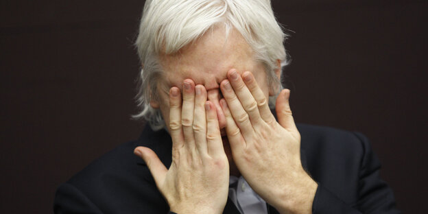 Julian Assange hält sich die Hände vor das Gesicht, das Bild zeigt ihn im Jahr 2011. Julian Assange hält sich die Hände vor das Gesicht, das Bild zeigt ihn im Jahr 2011.