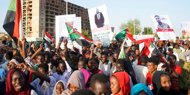 Menschen mit sudanesischen Flaggen und Plakaten demonstrieren in Khartum Menschen mit sudanesischen Flaggen und Plakaten demonstrieren in Khartum
