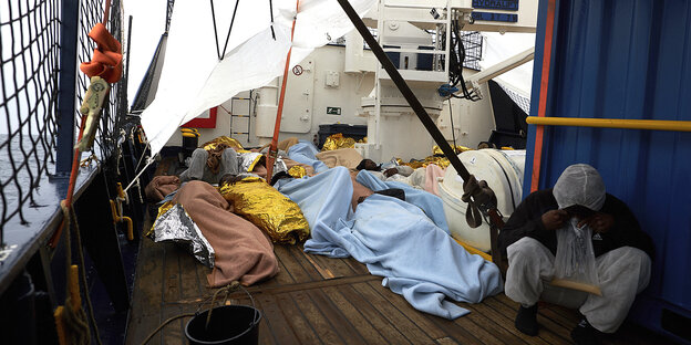 Menschen liegen aneinandergedrängt auf dem Deck eines schiffes Menschen liegen aneinandergedrängt auf dem Deck eines schiffes