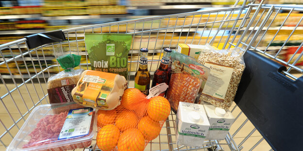 Bioprodukte in einem Einkaufswagen, der an Supermarktregalen vorbeirollt Bioprodukte in einem Einkaufswagen, der an Supermarktregalen vorbeirollt