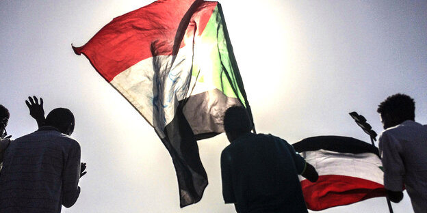 Sudanesische Demonstrierende laufen mit ihrer Flagge herum Sudanesische Demonstrierende laufen mit ihrer Flagge herum