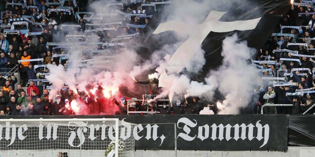Bengalos werden auf einer Tribüne gezündet - hinter einem Transpi mit Frakturschrift Bengalos werden auf einer Tribüne gezündet - hinter einem Transpi mit Frakturschrift
