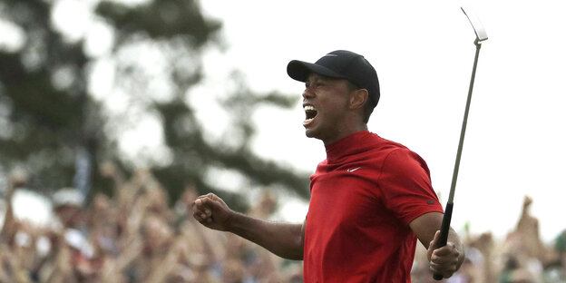 Tiger Woods freut sich, er hält einen Golfschläger in die Höhe Tiger Woods freut sich, er hält einen Golfschläger in die Höhe