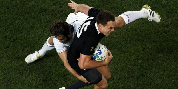Zwei Sportler kämpfen sich auf eineem Rasenplatz um den Rugbyball Zwei Sportler kämpfen sich auf eineem Rasenplatz um den Rugbyball