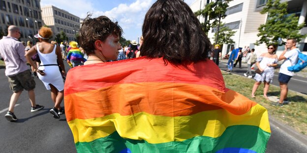 Zwei Frauen hüllen sich in eine Regenbogen-Fahne Zwei Frauen hüllen sich in eine Regenbogen-Fahne
