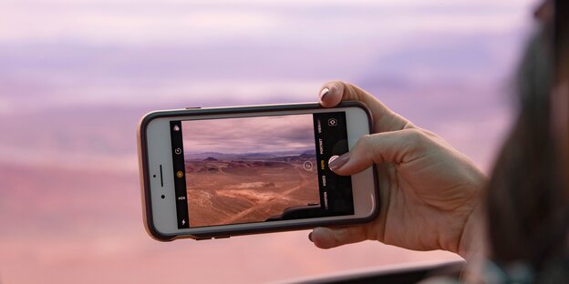 Eine Hand macht ein Foto von einer schönen Wüstenlandschaft Eine Hand macht ein Foto von einer schönen Wüstenlandschaft