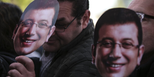 Menschen tragen Masken vom Oppositionskandidaten Ekrem Imamoglu Menschen tragen Masken vom Oppositionskandidaten Ekrem Imamoglu