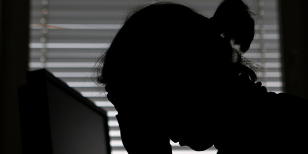 Frau vor Monitor fasst sich an den gesenkten Kopf Frau vor Monitor fasst sich an den gesenkten Kopf