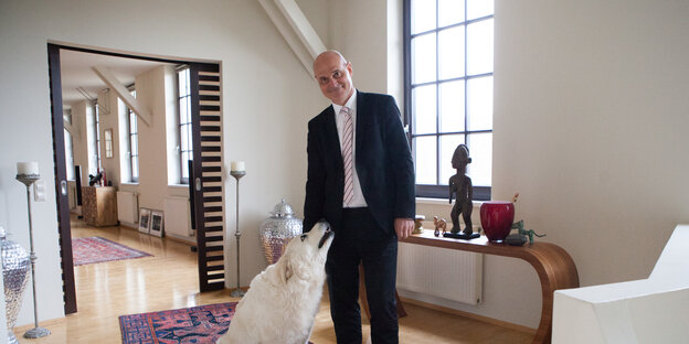 Ein Mann mit einem weißen Hund in einem hellen Raum Ein Mann mit einem weißen Hund in einem hellen Raum