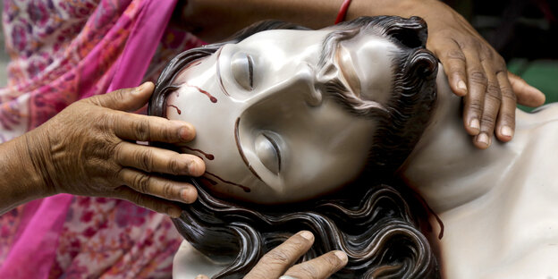 Indische Katholikinnen fassen ein Tonmodell von Jesus Christus an Indische Katholikinnen fassen ein Tonmodell von Jesus Christus an