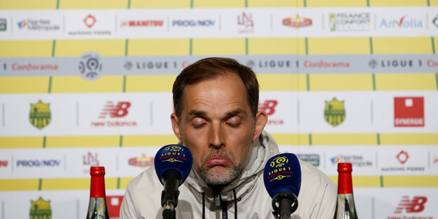 Thomas Tuchel sitzt auf einer Pressekonferenz und guckt traurig