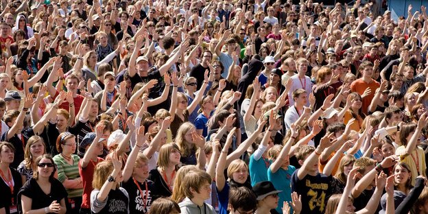 Evangelikale stehen in einer Menschenmenge und heben die Hände Evangelikale stehen in einer Menschenmenge und heben die Hände