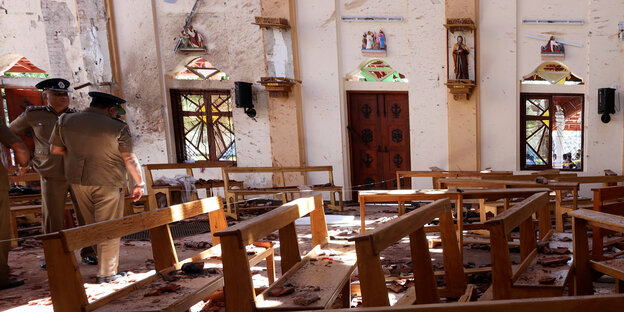 Polizisten stehen in einer zerstörten Kirche Polizisten stehen in einer zerstörten Kirche