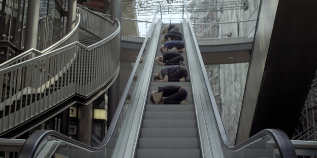 Menschen kauern auf einer Rolltreppe Menschen kauern auf einer Rolltreppe