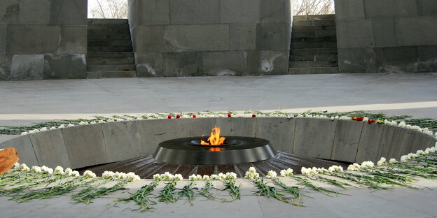 Um eine Flamme herum sind Blumen abgelegt Um eine Flamme herum sind Blumen abgelegt