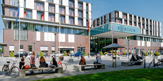 Menschen sitzen auf Bänken vor dem Haupteingang des Universitätsklinikums Eppendorf. Menschen sitzen auf Bänken vor dem Haupteingang des Universitätsklinikums Eppendorf.