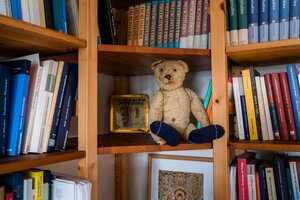 Ein Bücherregal in dem neben Büchern auch ein Teddy sitzt Ein Bücherregal in dem neben Büchern auch ein Teddy sitzt