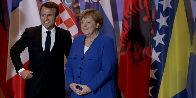 Merkel und Macron posieren vor Flaggen