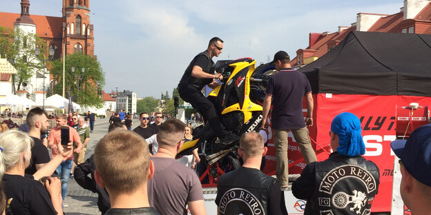 Ein Mann auf einem Motorrad vor einer jubelnden Menge Ein Mann auf einem Motorrad vor einer jubelnden Menge