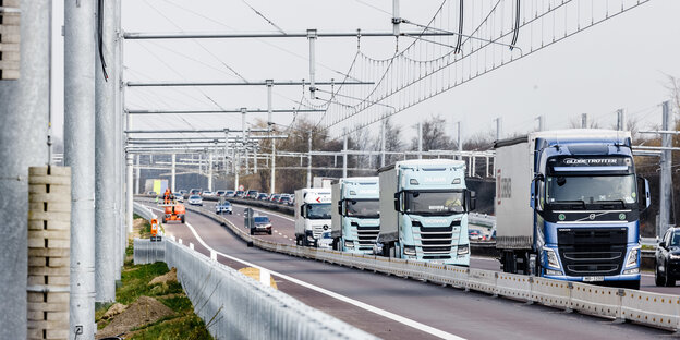 Lastwagenkolonne auf der Autobahn neben der künftigen Oberleitungsspur Lastwagenkolonne auf der Autobahn neben der künftigen Oberleitungsspur