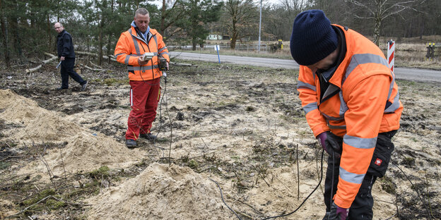 Zwei Personen in Warnwesten arbeiten im Sand Zwei Personen in Warnwesten arbeiten im Sand