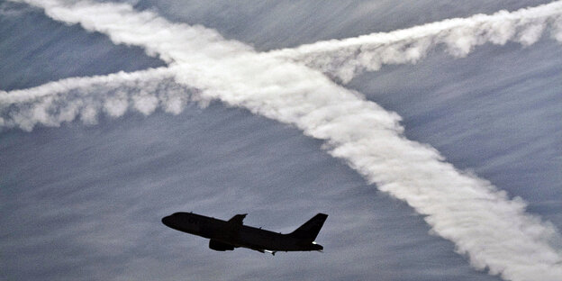 Ein Flugzeug vor zwei sich kreuzenden Kondensstreifen am blauen Himmel Ein Flugzeug vor zwei sich kreuzenden Kondensstreifen am blauen Himmel