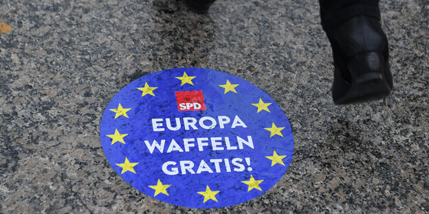 Ein Mensch läuft über einen SPD-Aufkleber mit der Aufschrift „Europa Waffeln gratis!“ Ein Mensch läuft über einen SPD-Aufkleber mit der Aufschrift „Europa Waffeln gratis!“