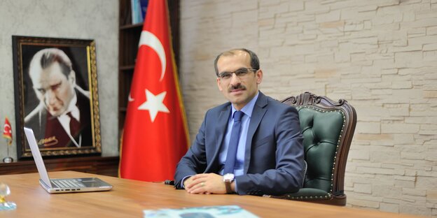 Ein Mann sitzt mit gefalteten Händen an seinem Schreibtisch. Neben ihm die Flagge der Türkei Ein Mann sitzt mit gefalteten Händen an seinem Schreibtisch. Neben ihm die Flagge der Türkei