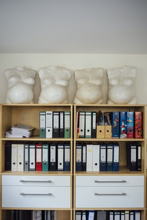 Ein Aktenschrank, auf dem vier lebensgroße Torsi aus Gips von schwangeren Frauenbäuchen stehen Ein Aktenschrank, auf dem vier lebensgroße Torsi aus Gips von schwangeren Frauenbäuchen stehen