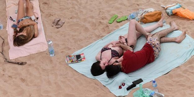 Menschen liegen auf Handtüchern auf dem Sand Menschen liegen auf Handtüchern auf dem Sand