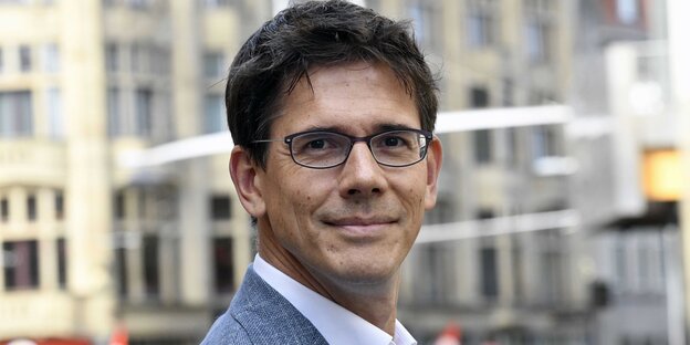 Ein Mann mit Brille und graublauem Jackett Ein Mann mit Brille und graublauem Jackett