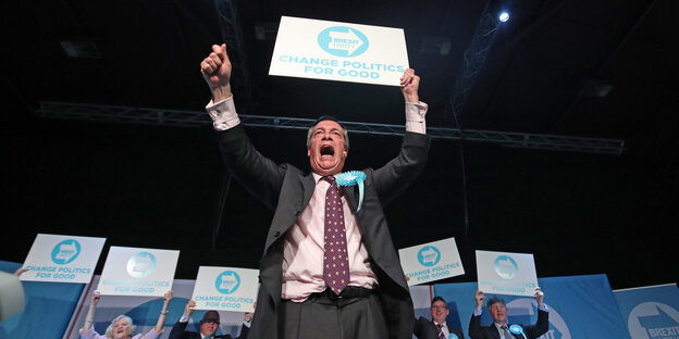 Nigel Farage hält ein Schild mit der Aufschrift "Brexit Party. Change Politics for good"