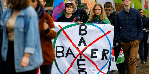 Umweltaktivisten protestieren mit einem weißem Banner, auf dem ein durchgestrichenes Bayer-Logo zu sehen ist. Umweltaktivisten protestieren mit einem weißem Banner, auf dem ein durchgestrichenes Bayer-Logo zu sehen ist.