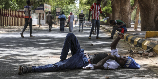 Ein Demonstrant ruht sich auf der Straße liegend aus, die zu der Sit-In-Demonstration vor den Militär-Hauptgebäude führt Ein Demonstrant ruht sich auf der Straße liegend aus, die zu der Sit-In-Demonstration vor den Militär-Hauptgebäude führt