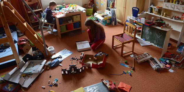 Zwei Kinder spielen in einem unordentlichen Kinderzimmer Zwei Kinder spielen in einem unordentlichen Kinderzimmer