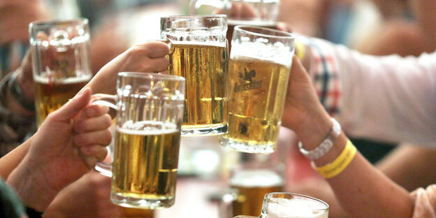 Menschen stoßen mit Bierkrügen an Menschen stoßen mit Bierkrügen an