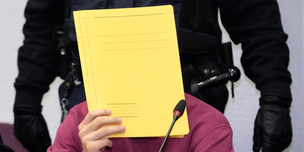 Ein Mann hält einen Hefter vor seinem Gesicht Ein Mann hält einen Hefter vor seinem Gesicht