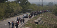 Migranten aus Mittelamerika gehen mit Rucksäcken auf dem Rückeneine Straße entlang