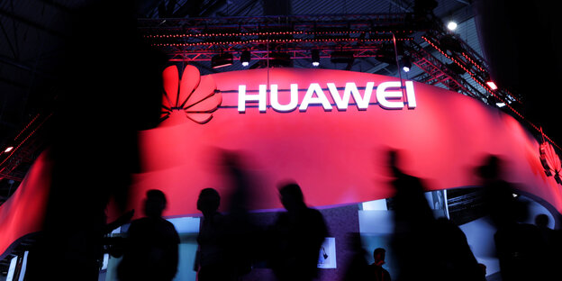 Menschen laufen an einem großen Huawei-Zeichen vorbei Menschen laufen an einem großen Huawei-Zeichen vorbei