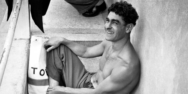 Der Schwimmer Alfred Nakache ist auf einem Schwarz-Weiß-Foto zu sehen, wie er mit nacktem Oberkörper auf einer Treppe sitzt Der Schwimmer Alfred Nakache ist auf einem Schwarz-Weiß-Foto zu sehen, wie er mit nacktem Oberkörper auf einer Treppe sitzt